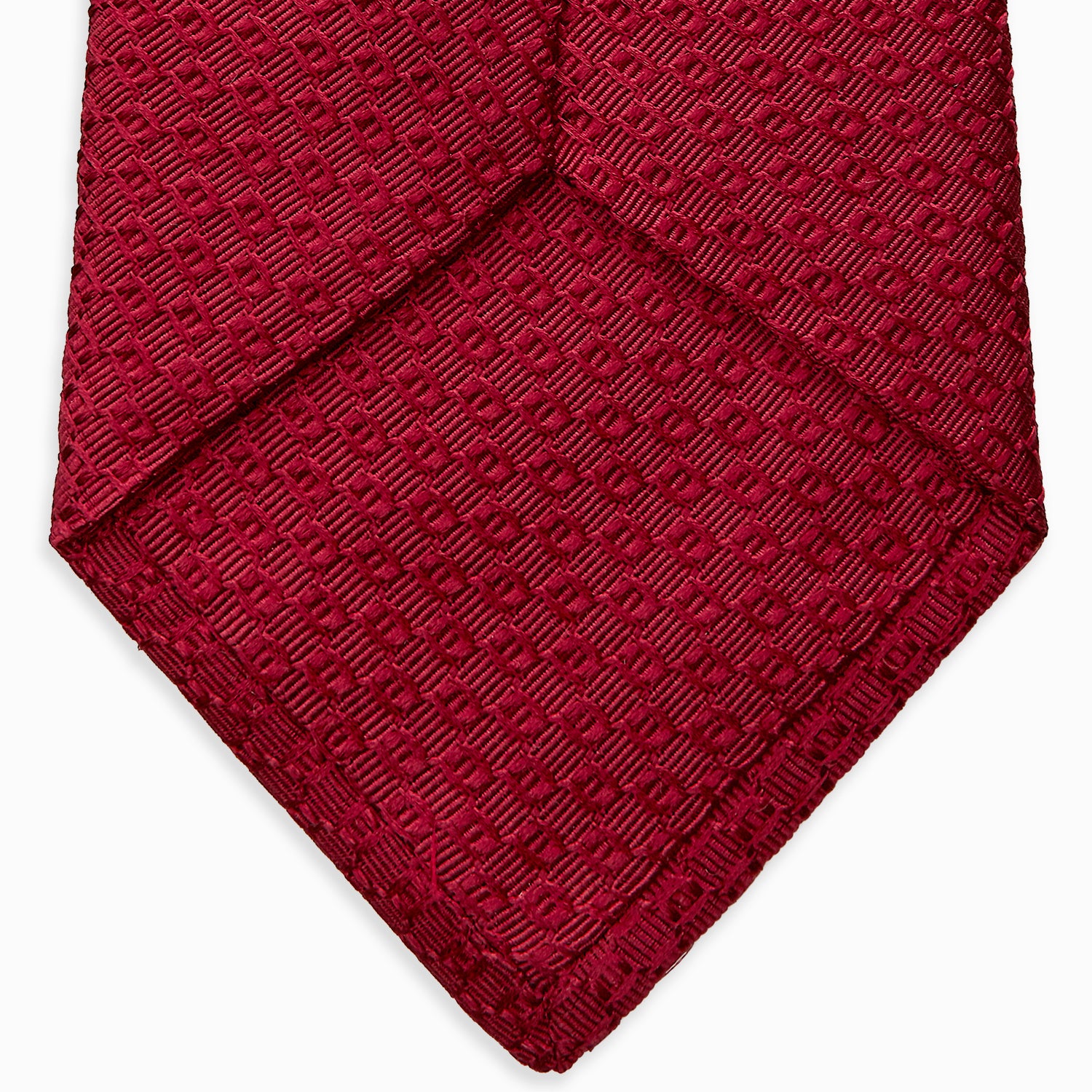 View 4 of product The Turnbull & Asser Burgundy Abstract Tonal Silk Jacquard Tie is shown rolled up with a subtle textured pattern on a plain white background—an elegant formalwear choice.