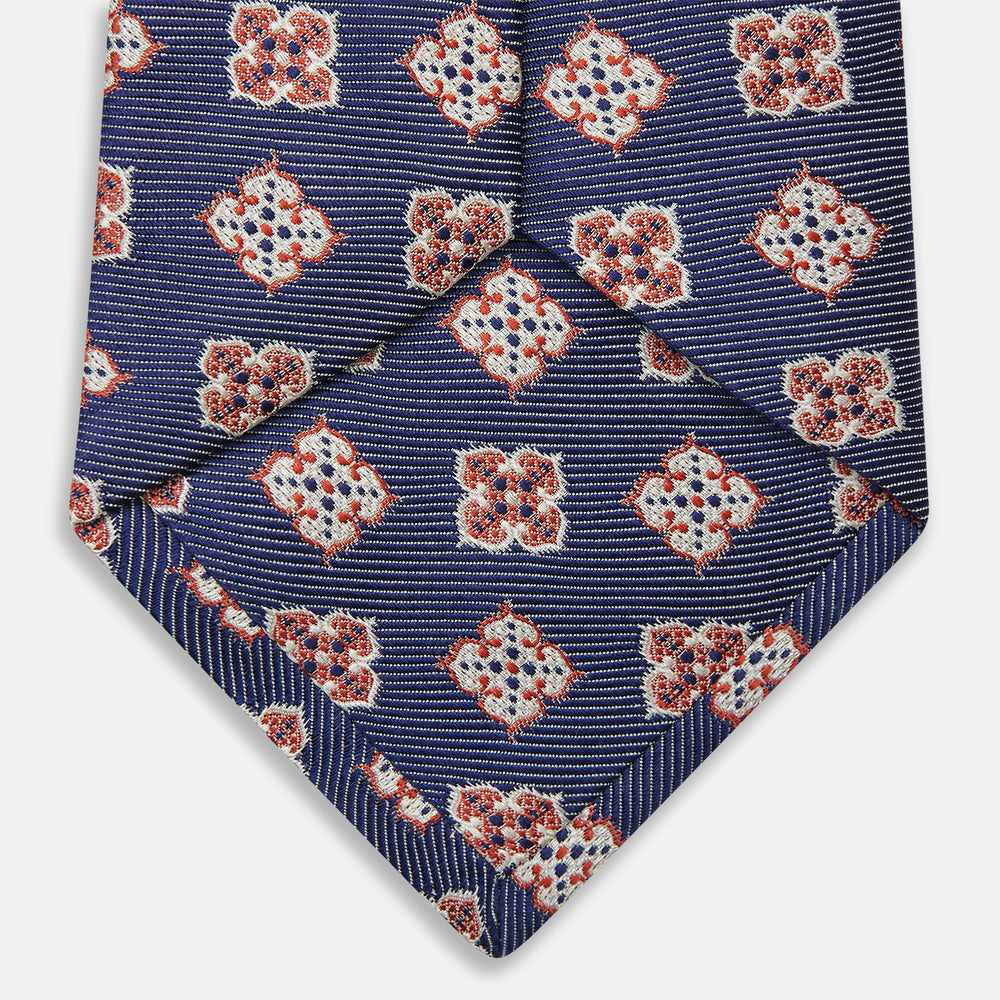The Turnbull & Asser Burgundy Geometric Jacquard Tie features a bold, playful pattern of red and white dice scattered across its surface.
