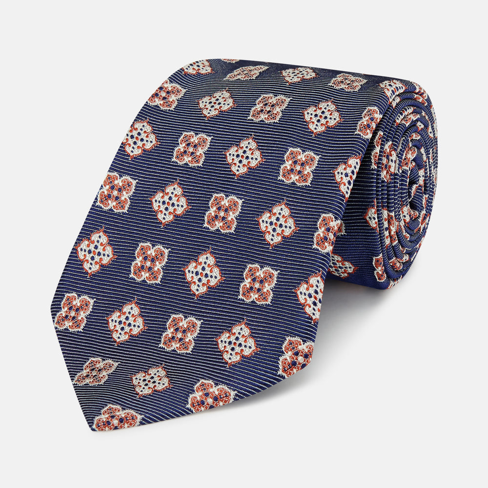 The Turnbull & Asser Burgundy Geometric Jacquard Tie features a bold, playful pattern of red and white dice scattered across its surface.