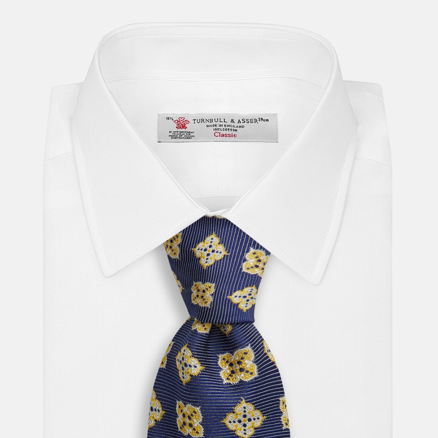 View 2 of product The Turnbull & Asser Yellow Geometric Jacquard Tie in navy features a repeating pattern of yellow geometric shapes with blue accents, presented rolled up on a white background.