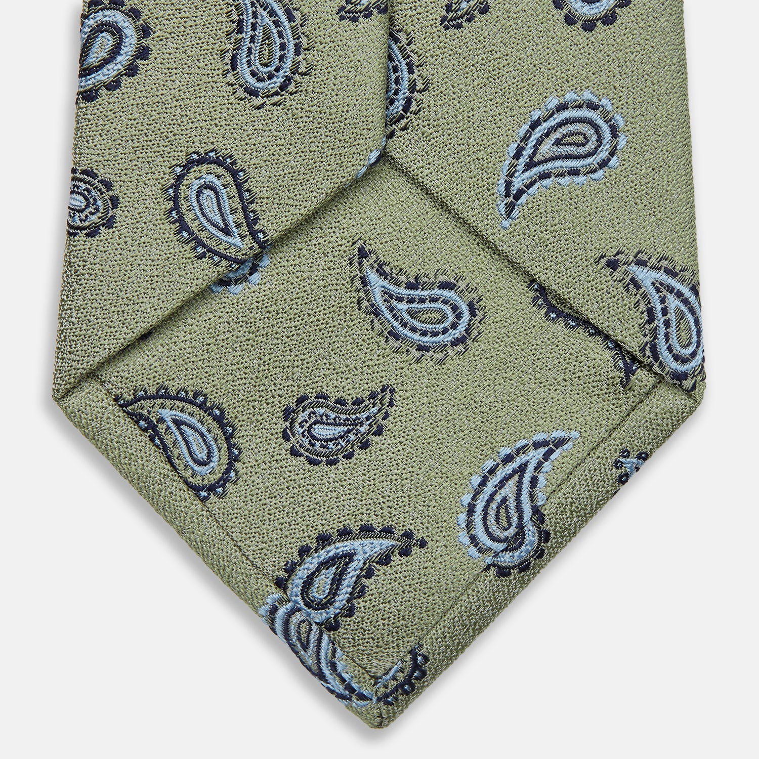 View 4 of product The Green Renoir Paisley Tie by Turnbull & Asser is a pistachio green jacquard tie with blue and black paisley motifs on a light background.
