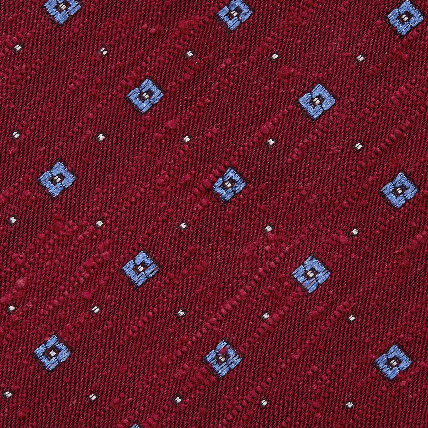 View 3 of product The Turnbull & Asser Red Square Silk Tie features a red and blue pattern with small white squares, elegantly rolled and displayed on a plain white background—a refined choice for men's accessories.