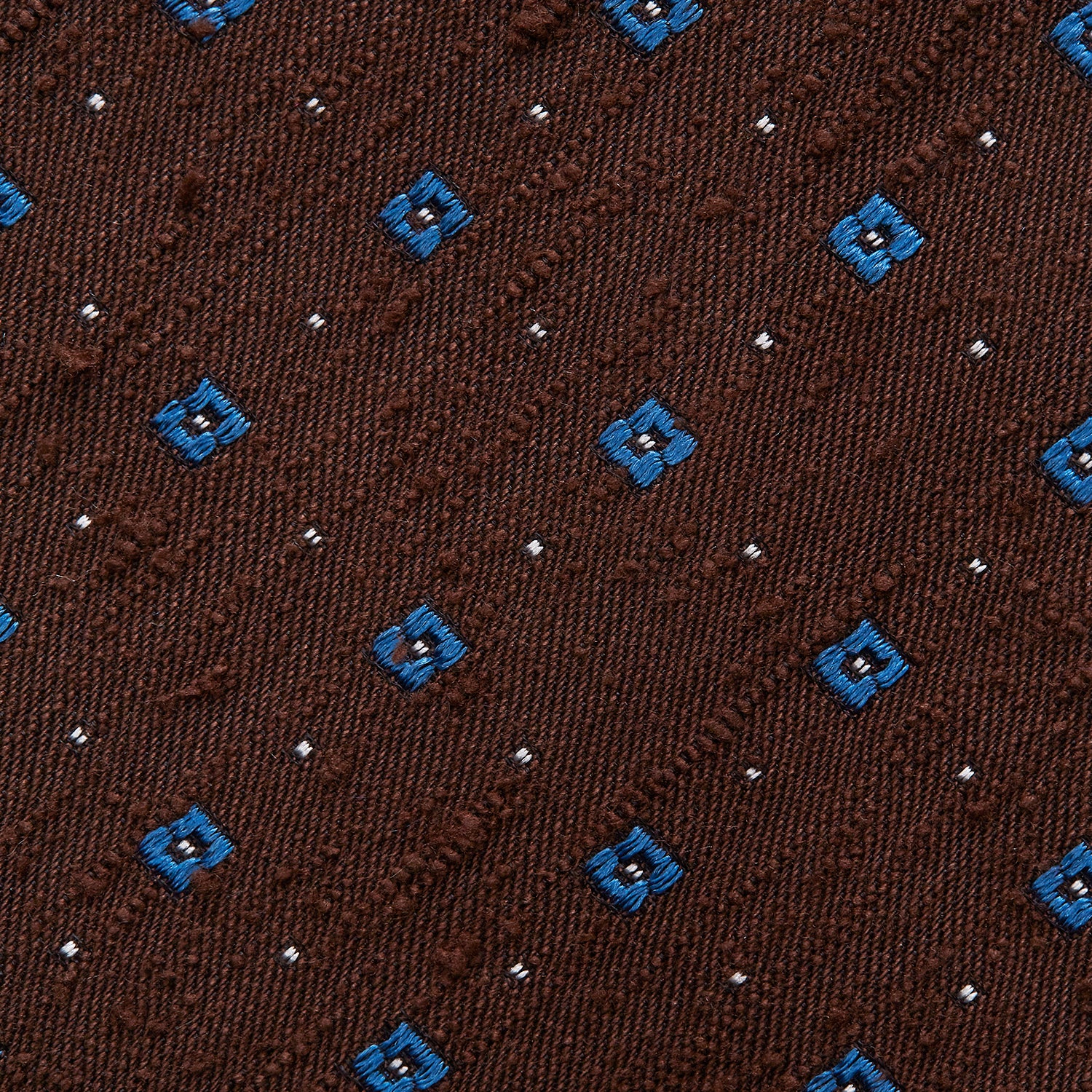 View 3 of product The Turnbull & Asser Brown Square Silk Tie, featuring a jacquard pattern of small blue squares and dots, is shown rolled up on a plain white background.