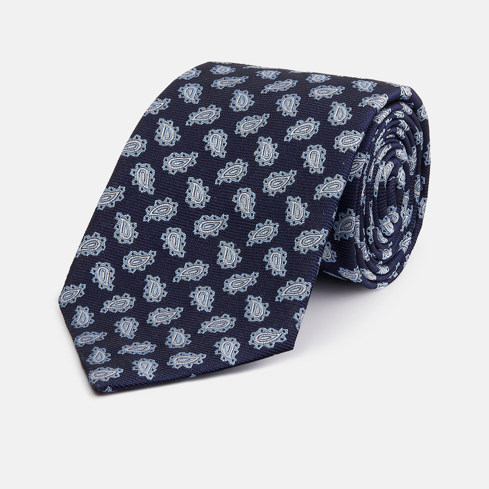 The Blue Abstract Paisley Silk Tie by Turnbull & Asser features a classic paisley motif in navy, offering a timeless touch to your wardrobe and perfectly capturing traditional elegance.