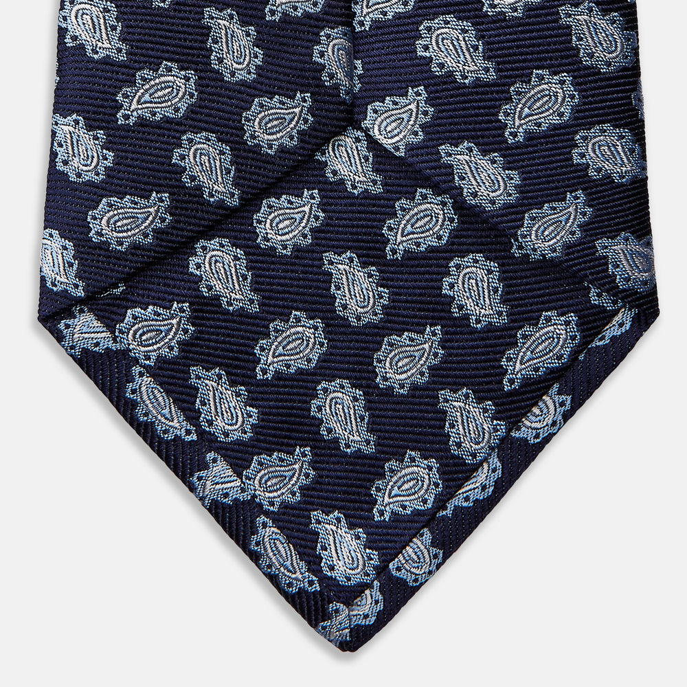 The Blue Abstract Paisley Silk Tie by Turnbull & Asser features a classic paisley motif in navy, offering a timeless touch to your wardrobe and perfectly capturing traditional elegance.