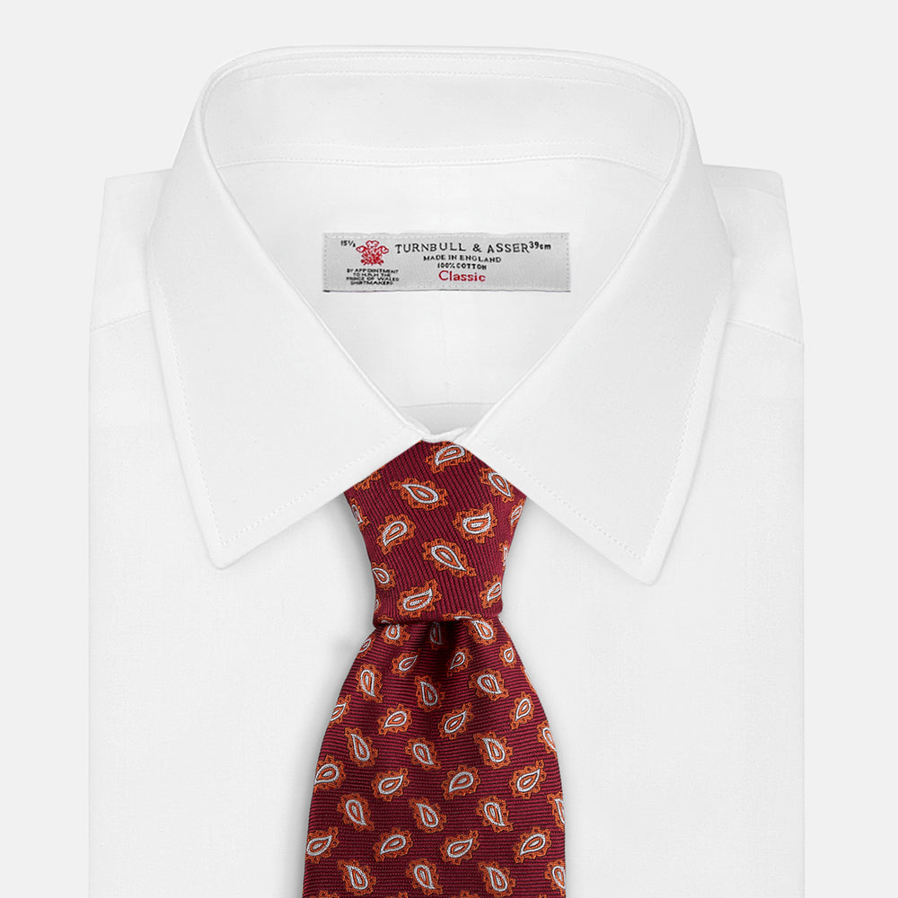The Turnbull & Asser Red Abstract Paisley Silk Tie features bold orange and white paisley patterns on rich red silk—a stylish choice for fans of classic tailoring.