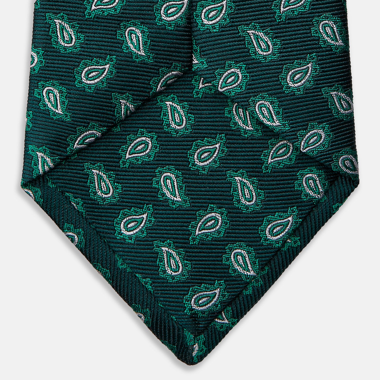 View 4 of product The Turnbull & Asser Green Abstract Paisley Silk Tie features a repeating light green paisley pattern on dark green silk, shown rolled up against a white background—a refined men’s accessory for making a statement.