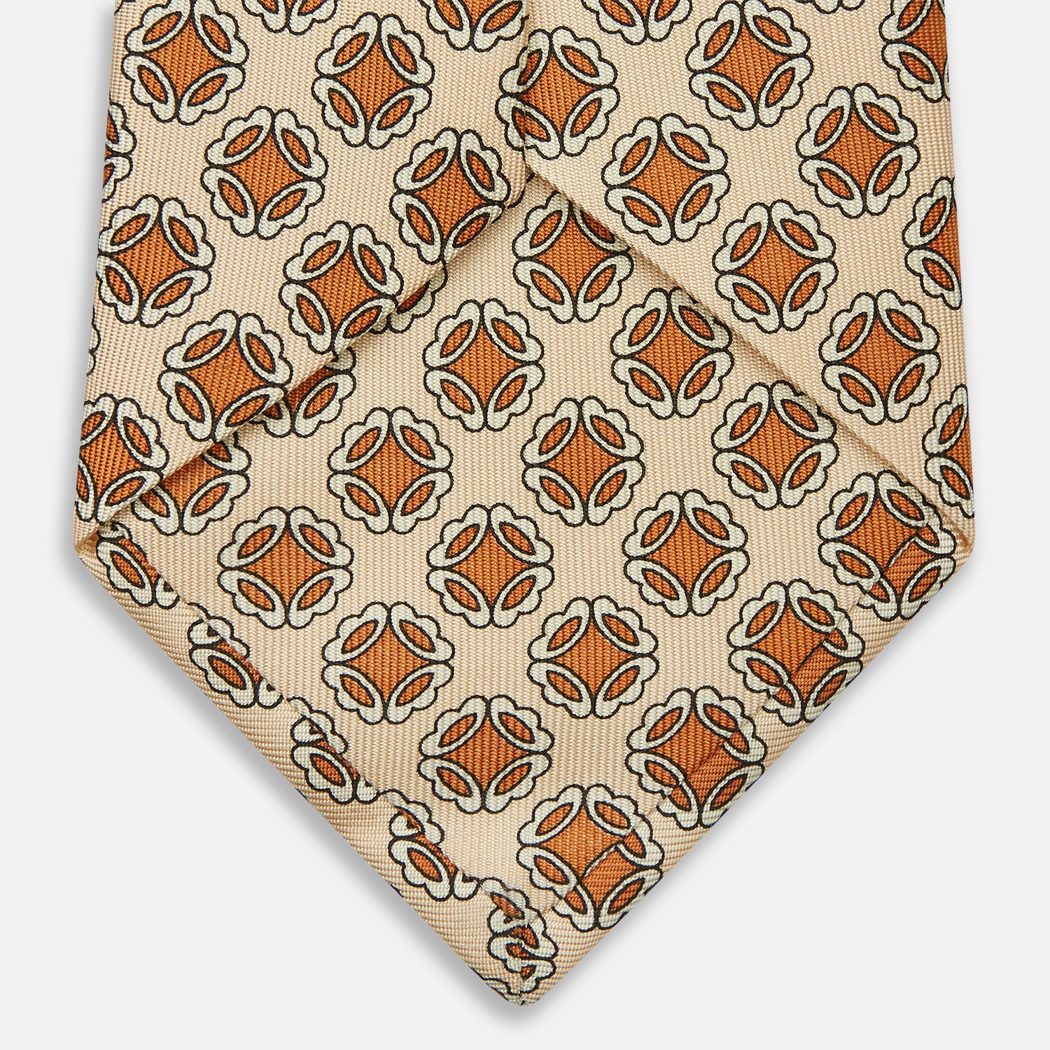 View 4 of product A cream floral geometric tie by Turnbull & Asser, rolled with the pointed end forward, is displayed on a white background.
