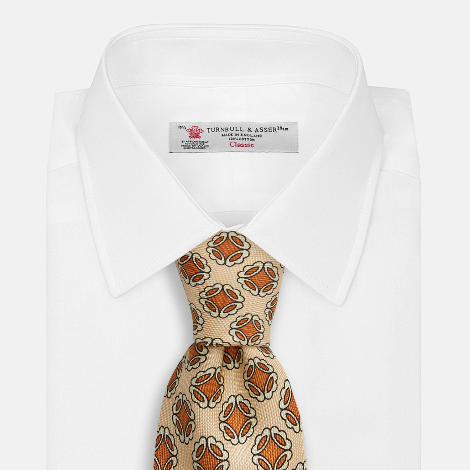 View 2 of product A cream floral geometric tie by Turnbull & Asser, rolled with the pointed end forward, is displayed on a white background.