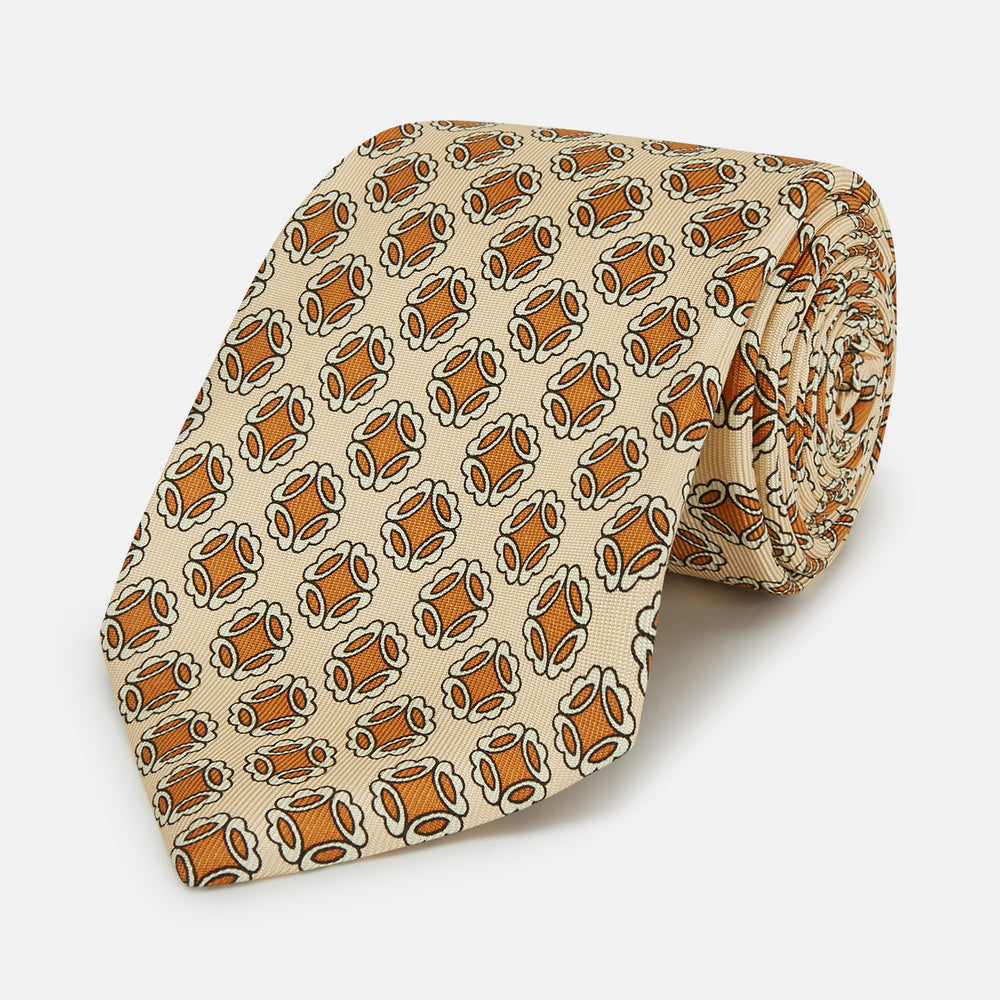 A cream floral geometric tie by Turnbull & Asser, rolled with the pointed end forward, is displayed on a white background.