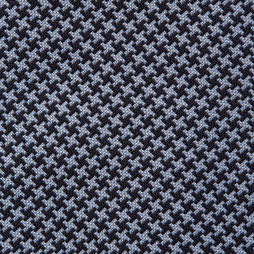 The Turnbull & Asser Blue Houndstooth Silk Tie, shown rolled on a plain white background, adds a refined touch to any sophisticated wardrobe.