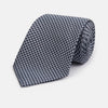 View 1 of product The Turnbull & Asser Blue Houndstooth Silk Tie, shown rolled on a plain white background, adds a refined touch to any sophisticated wardrobe.