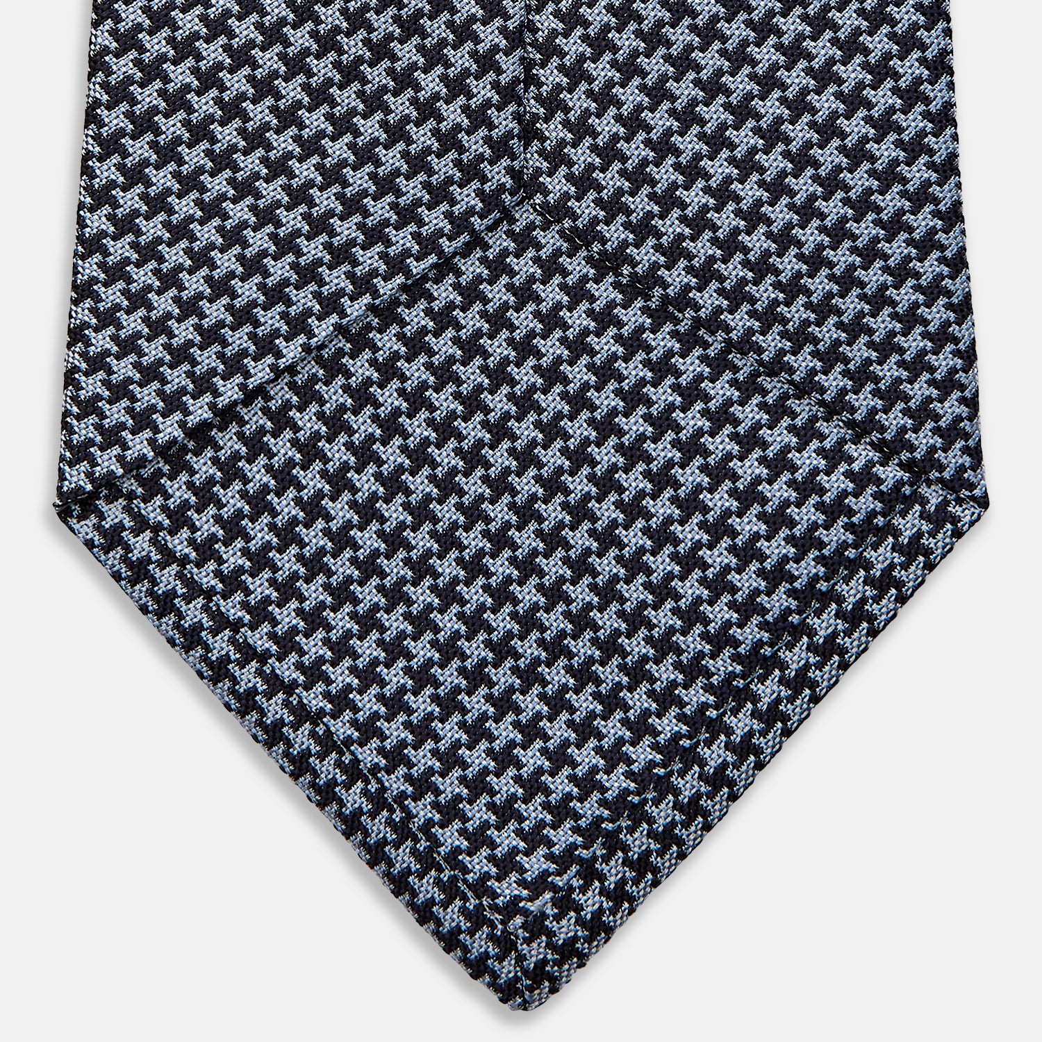 View 4 of product The Turnbull & Asser Blue Houndstooth Silk Tie, shown rolled on a plain white background, adds a refined touch to any sophisticated wardrobe.