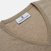 View 2 of product The Beige Paden V-Neck Jumper by Turnbull & Asser, made of pure cashmere, features long sleeves and ribbed cuffs and hem. It is shown flat on a white background with the label visible at the neckline.