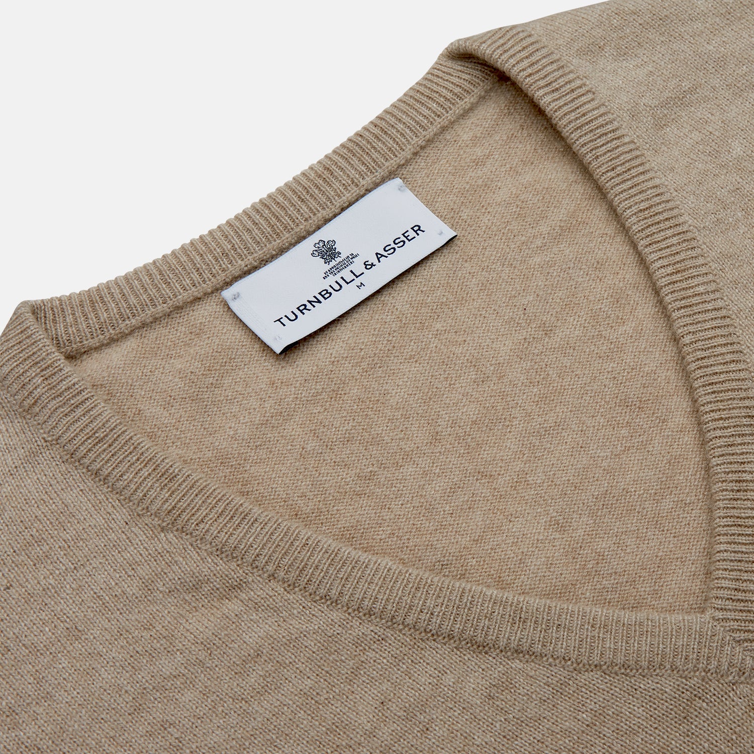 View 2 of product The Beige Paden V-Neck Jumper by Turnbull & Asser, made of pure cashmere, features long sleeves and ribbed cuffs and hem. It is shown flat on a white background with the label visible at the neckline.
