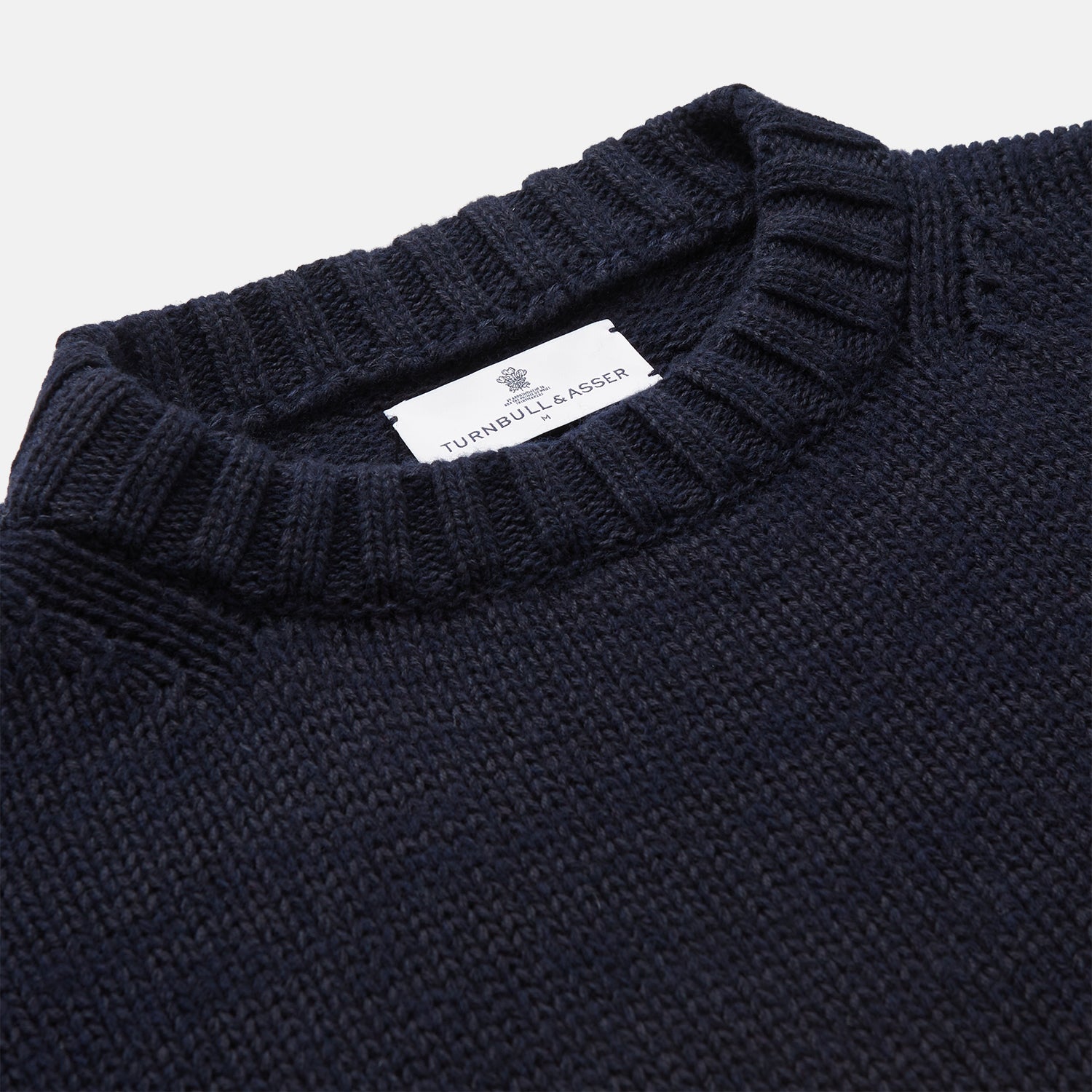 View 3 of product A man stands in the Turnbull & Asser Navy Lewis Guernsey Knitted Jumper.