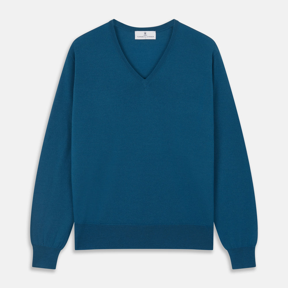 The Turnbull & Asser Ocean Blue Merino Kennedy V-Neck Jumper, shown flat on a white background, features ribbed cuffs and hem with a visible branded label at the neckline.