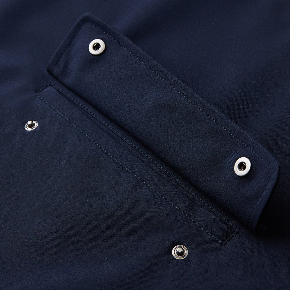 The Turnbull & Asser Navy Walter Sealup Parka with Detachable Liner features silver snap buttons, front flap pockets, and a drawstring hem. Styled against a white background, this waterproof parka offers both elegance and practicality for wet weather.