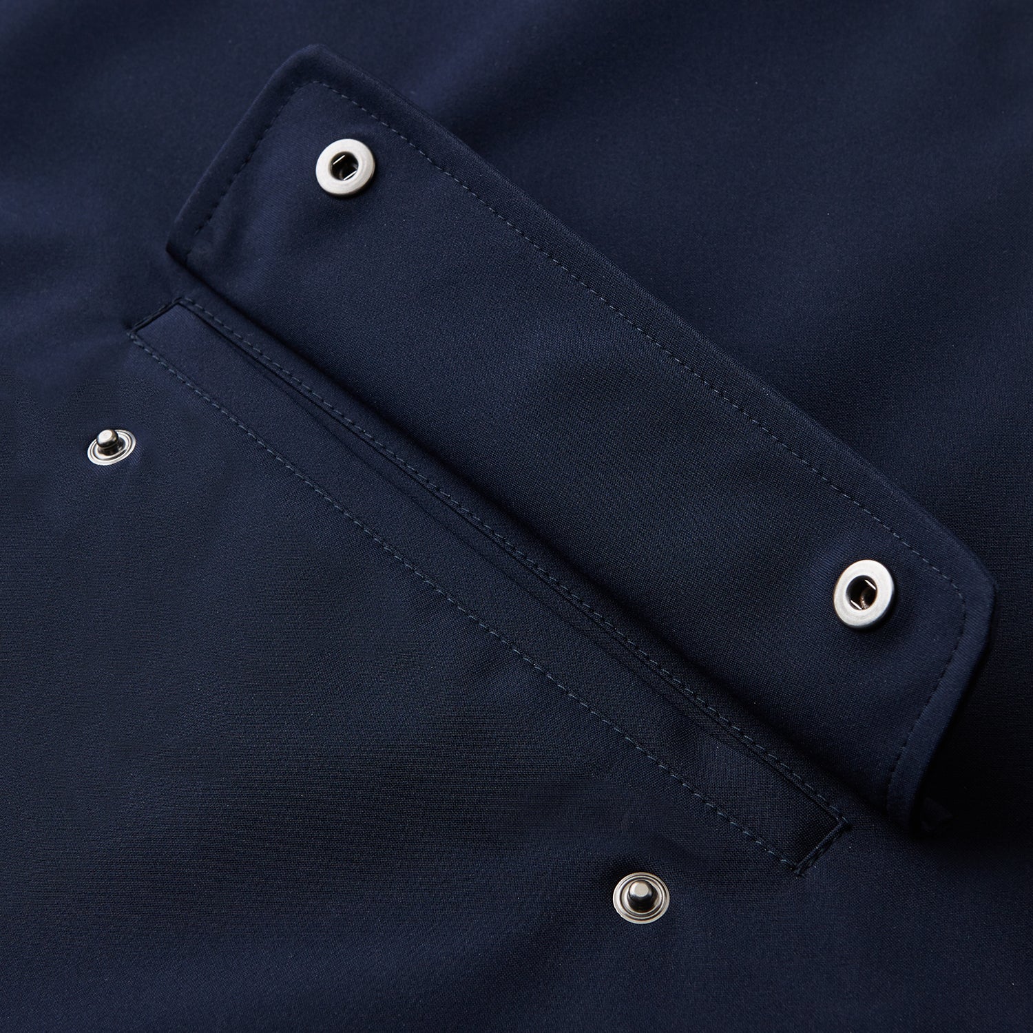 View 3 of product The Turnbull & Asser Navy Walter Sealup Parka with Detachable Liner features silver snap buttons, front flap pockets, and a drawstring hem. Styled against a white background, this waterproof parka offers both elegance and practicality for wet weather.