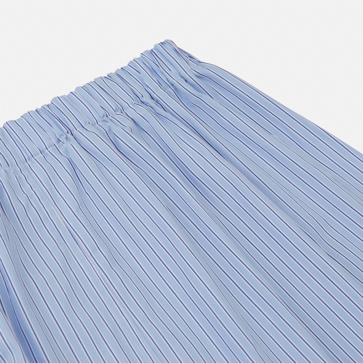 View 3 of product A man stands barefoot against a plain background, wearing a white short-sleeve T-shirt and Turnbull & Asser Blue Stripe Cotton Pyjama Trousers in a contemporary fit, looking straight ahead with a neutral expression.