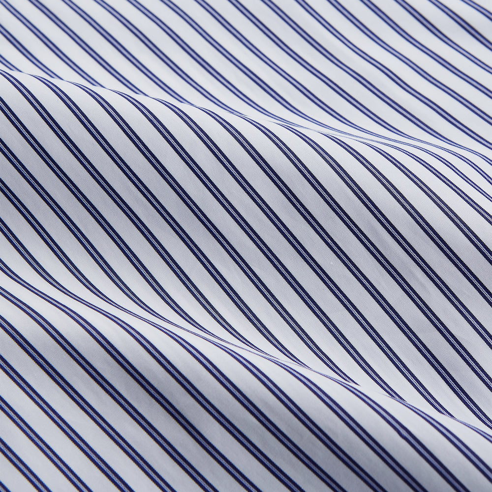 The Women's Dara Navy Stripe Pyjama Set by Turnbull & Asser features a long-sleeve button-up shirt with chest pocket and drawstring pants in premium cotton, shown neatly on a white background.