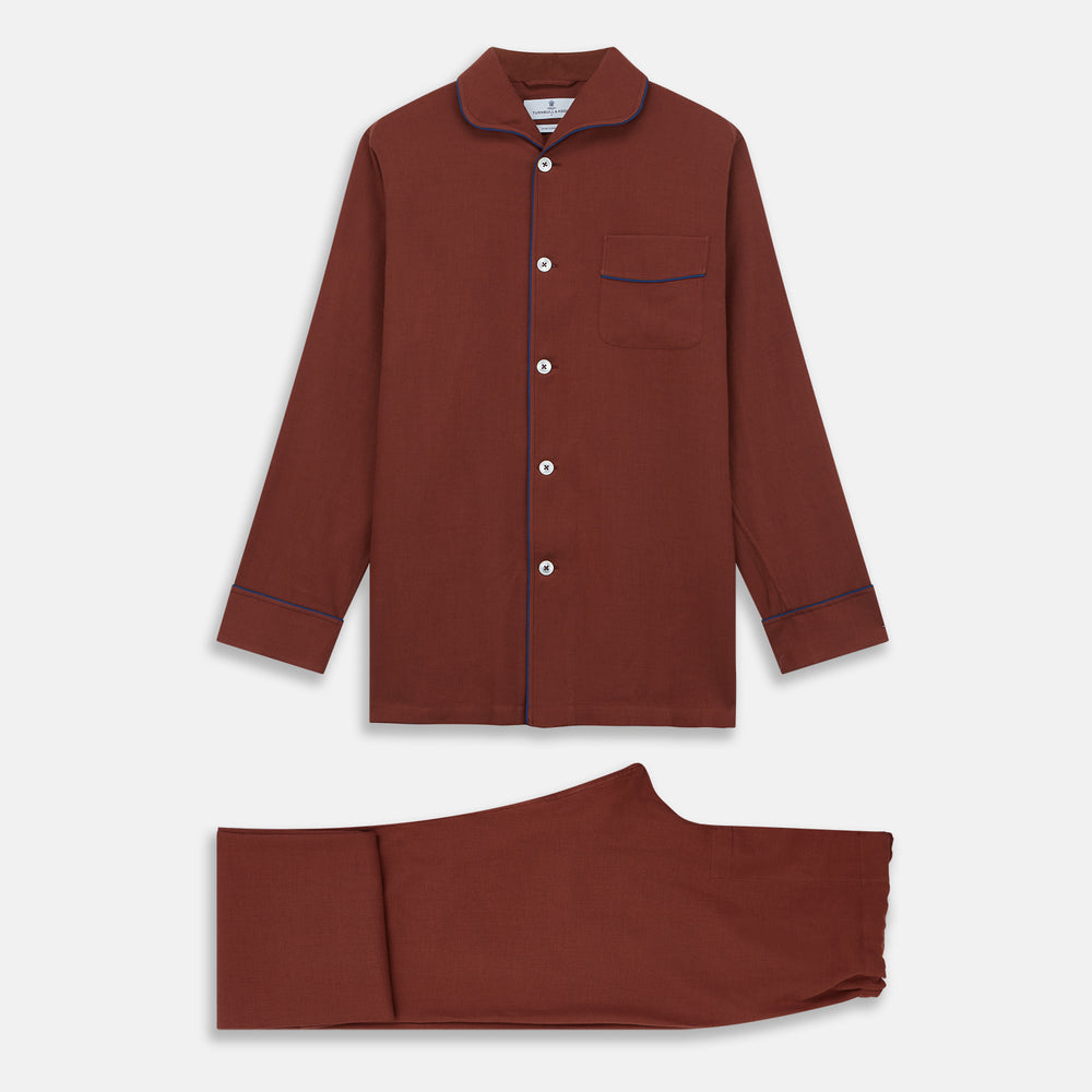 The Turnbull & Asser Red Cotton-Cashmere Pyjama Set features a rust-red long-sleeve button-up top with chest pocket and matching waist-tied pants, shown on a plain white background.