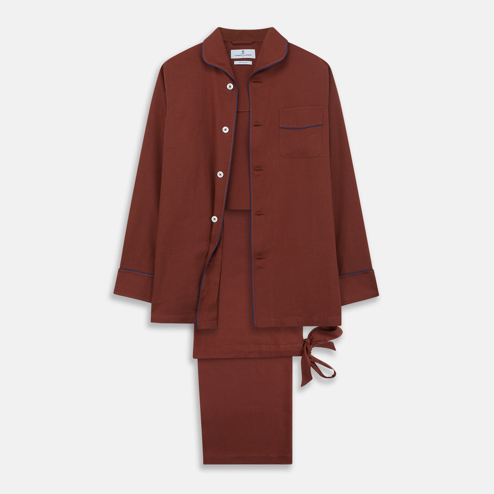 The Turnbull & Asser Red Cotton-Cashmere Pyjama Set features a rust-red long-sleeve button-up top with chest pocket and matching waist-tied pants, shown on a plain white background.