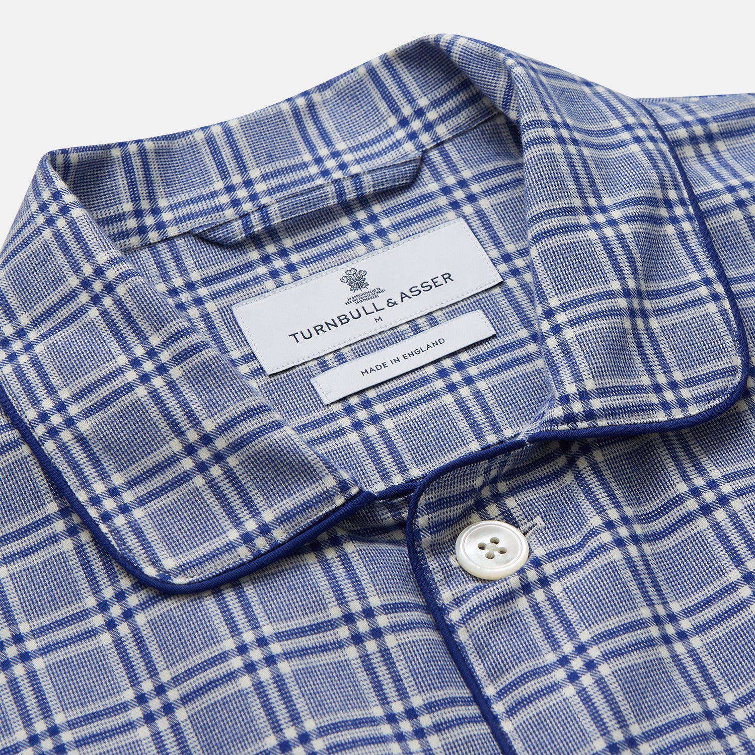 View 2 of product The Turnbull & Asser Blue Check Modern Cotton Pyjama Set features a long-sleeve button-up top and matching pants, crafted from thicker cotton for added comfort, shown against a white background.