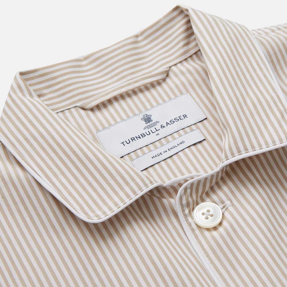 The Turnbull & Asser Sand Bengal Stripe Modern Fit Cotton Pyjama Set features cream-colored striped Italian cotton, with a long-sleeved button-up top and matching drawstring pants, neatly displayed against a white background.