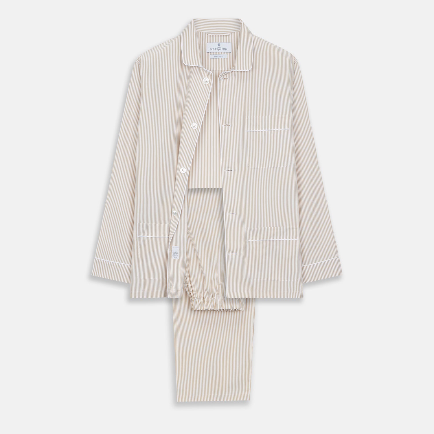 View 1 of product The Turnbull & Asser Sand Bengal Stripe Modern Fit Cotton Pyjama Set features cream-colored striped Italian cotton, with a long-sleeved button-up top and matching drawstring pants, neatly displayed against a white background.