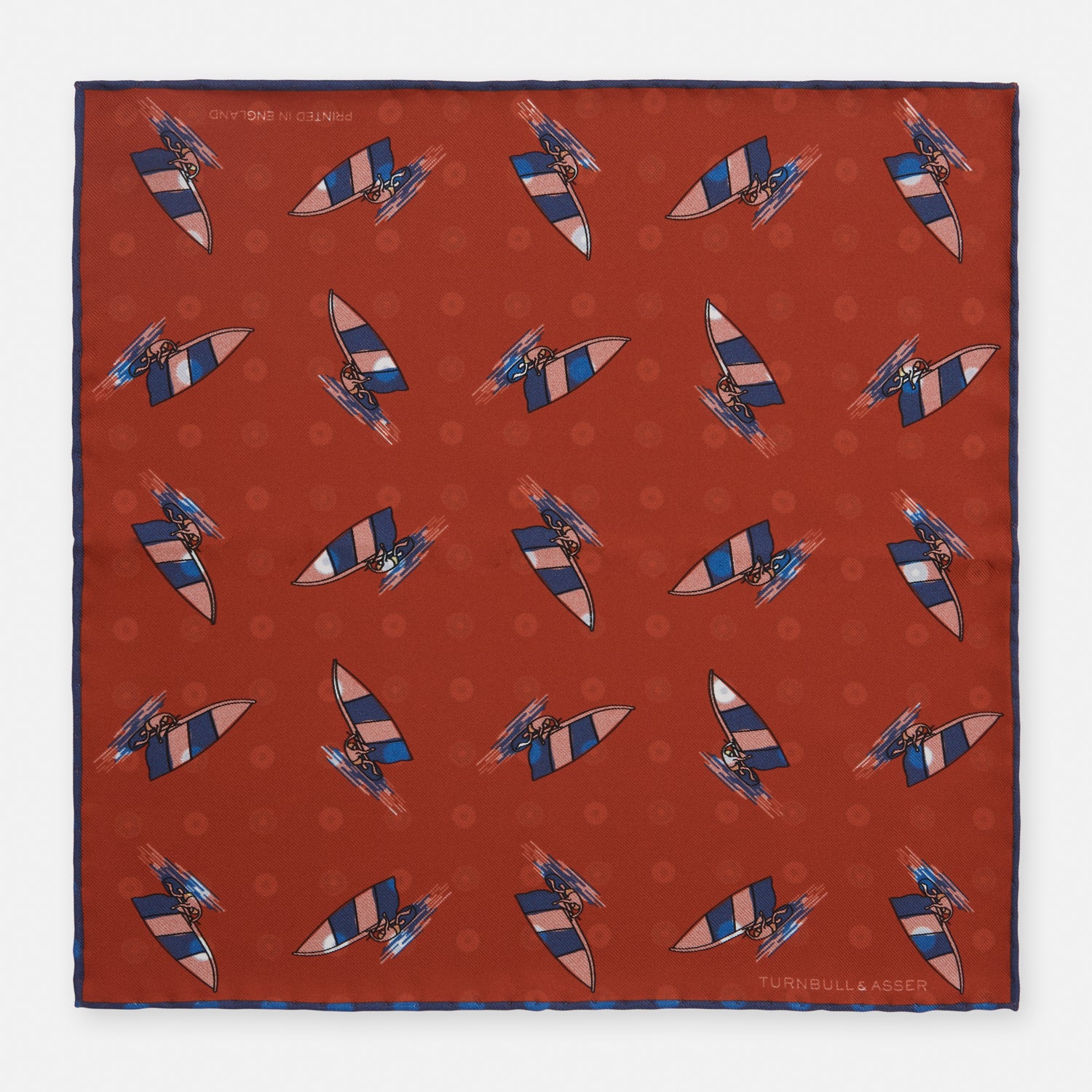 View 1 of product The Turnbull & Asser Red Windsurfer Double-Faced Silk Print Pocket Square features a vibrant windsurfer pattern on silk with a dark blue border and the brand subtly printed in one corner.