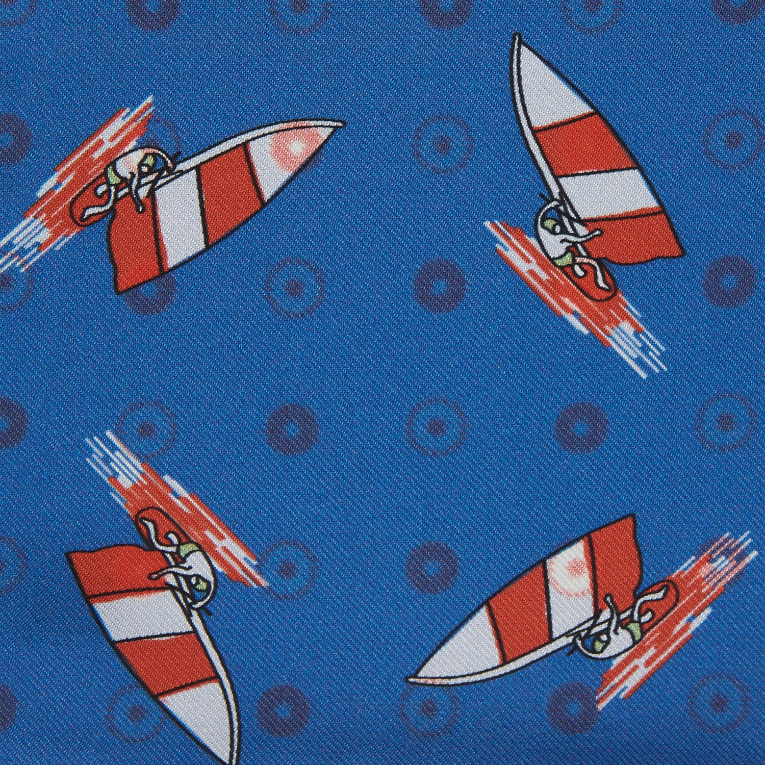 View 3 of product The Turnbull & Asser Blue Windsurfer Double-Faced Silk Print Pocket Square features a blue silk design with colorful windsurfers and vivid red edges, finished with the Turnbull & Asser logo in one corner.