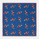 The Turnbull & Asser Blue Windsurfer Double-Faced Silk Print Pocket Square features a blue silk design with colorful windsurfers and vivid red edges, finished with the Turnbull & Asser logo in one corner.