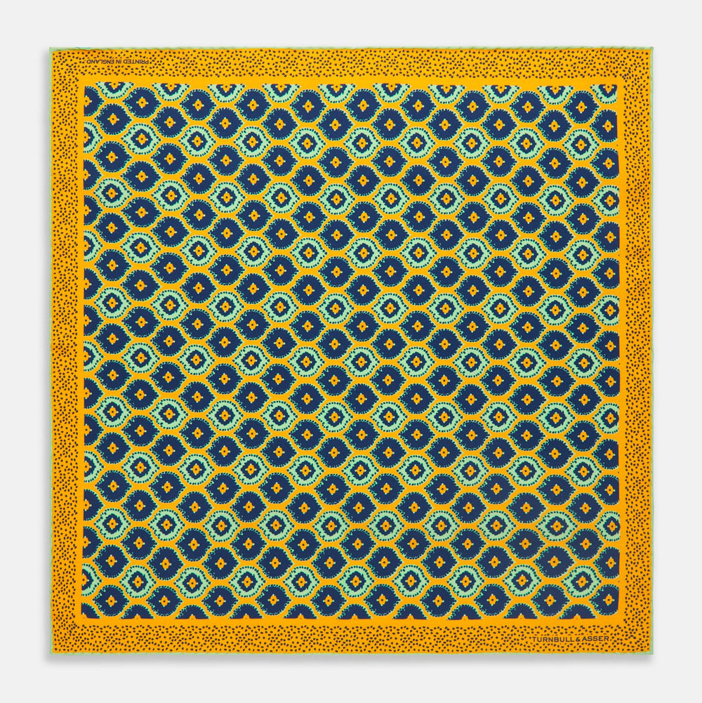 The Yellow Medallion Print Silk Pocket Square by Turnbull & Asser features blue hexagons with ochre yellow centers on a dark blue background, bordered by a dotted ochre yellow frame—a stylish accessory for any suit.