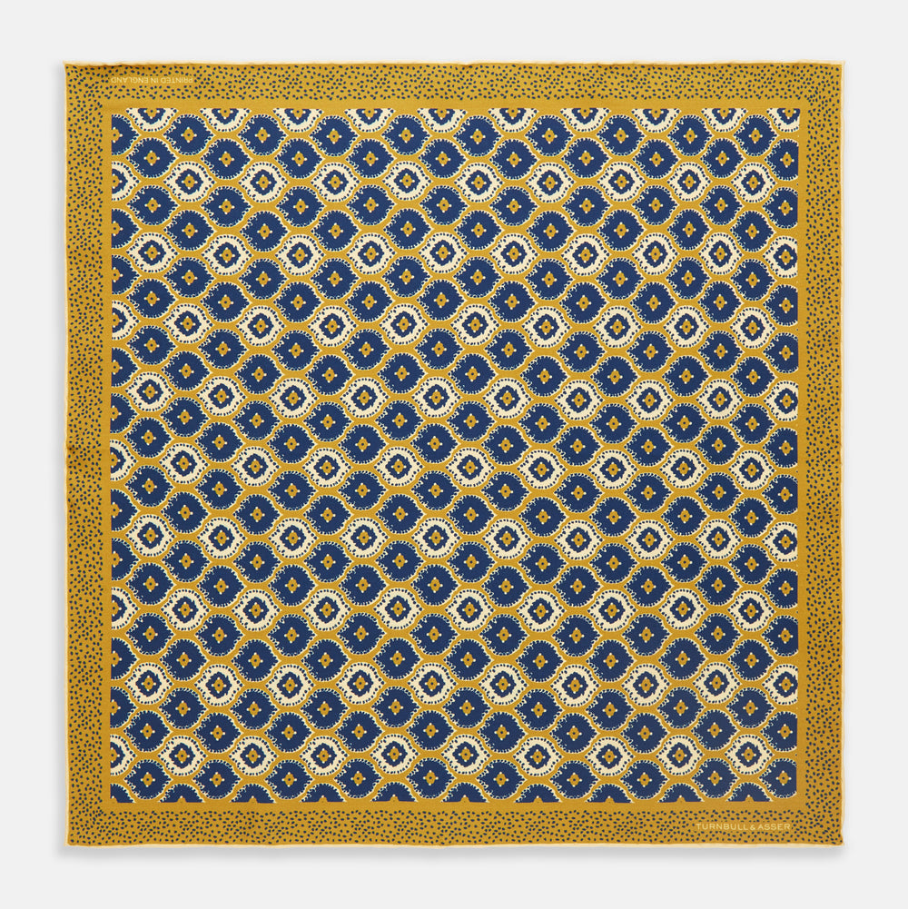 The Tan Medallion Print Silk Pocket Square by Turnbull & Asser features an elegant medallion geometric pattern in blue, white, and gold with central diamond shapes and a gold dotted border on luxurious silk.