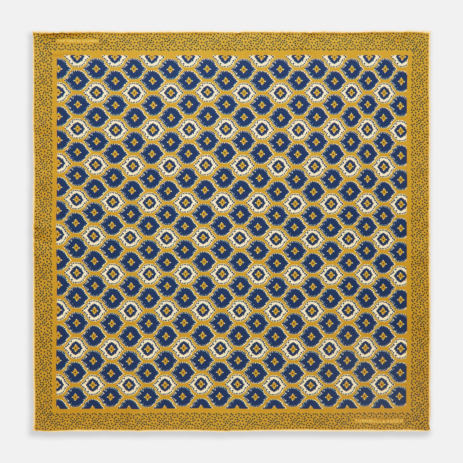 View 1 of product The Tan Medallion Print Silk Pocket Square by Turnbull & Asser features an elegant medallion geometric pattern in blue, white, and gold with central diamond shapes and a gold dotted border on luxurious silk.