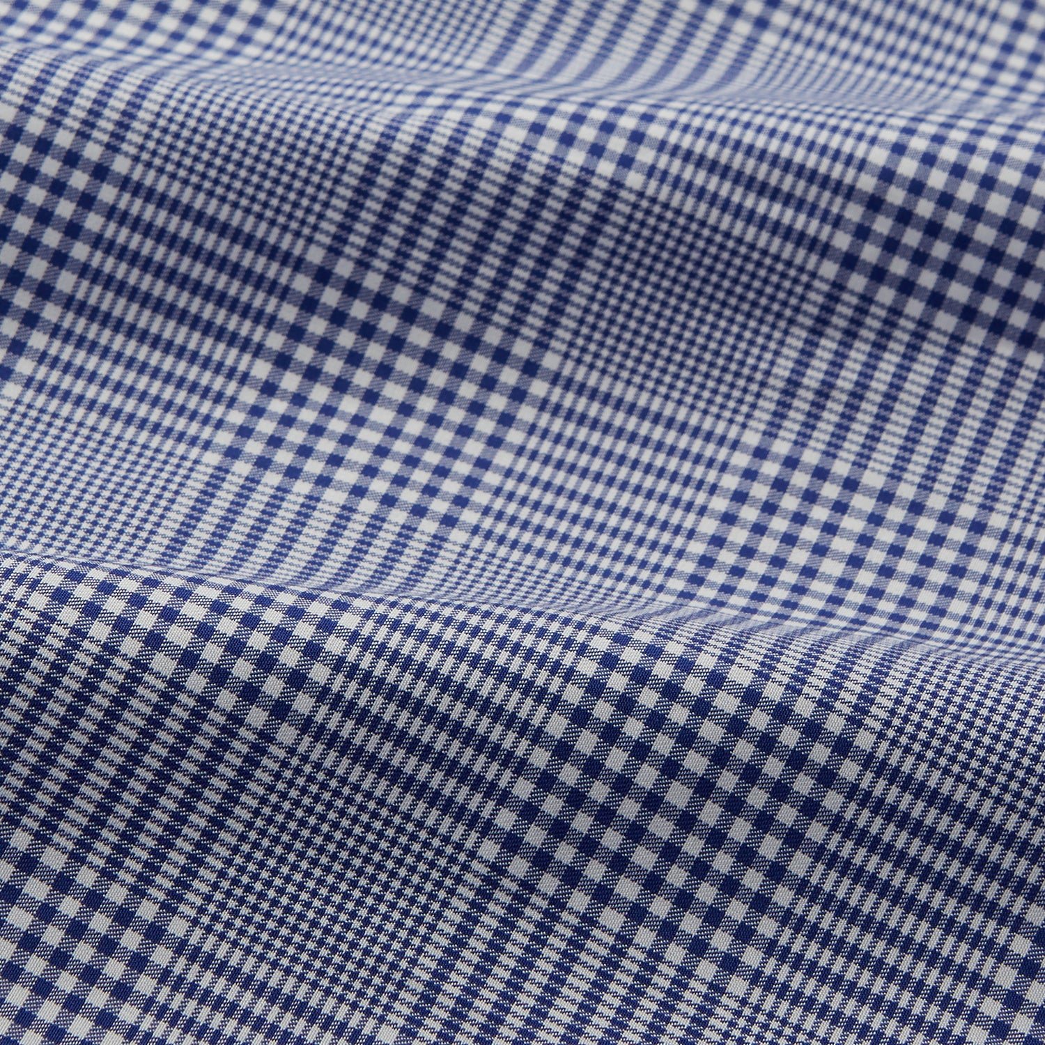 View 4 of product The Turnbull & Asser Navy Check Cotton Gown features long sleeves, white piping, a shawl collar, chest pocket, and matching waist belt, all in a blue plaid pattern. Shown against a plain white background.