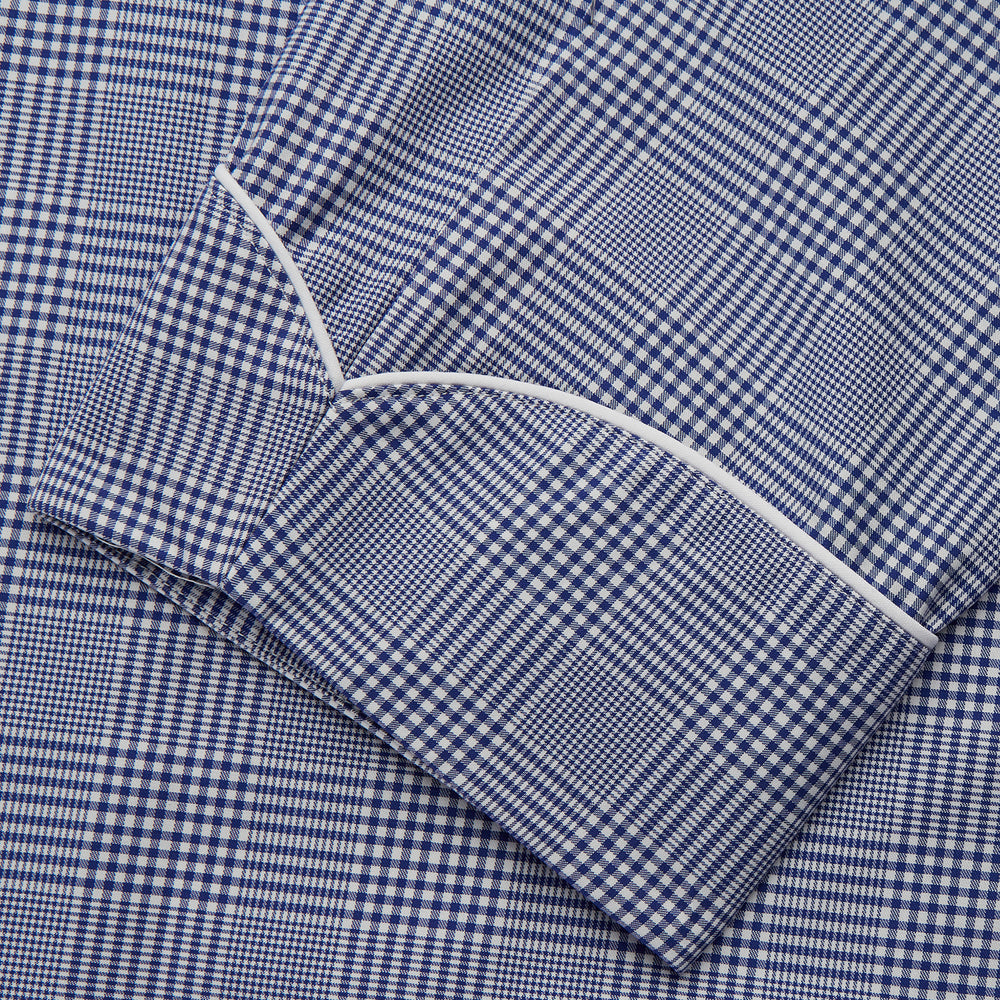 The Turnbull & Asser Navy Check Cotton Gown features long sleeves, white piping, a shawl collar, chest pocket, and matching waist belt, all in a blue plaid pattern. Shown against a plain white background.
