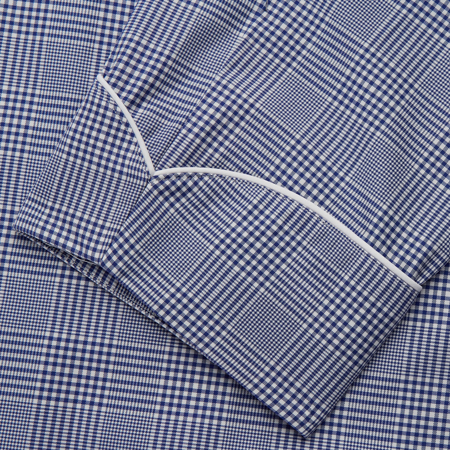 View 3 of product The Turnbull & Asser Navy Check Cotton Gown features long sleeves, white piping, a shawl collar, chest pocket, and matching waist belt, all in a blue plaid pattern. Shown against a plain white background.