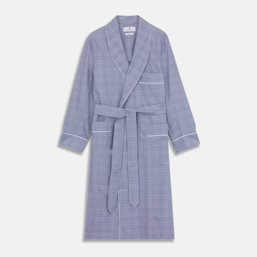 The Turnbull & Asser Navy Check Cotton Gown features long sleeves, white piping, a shawl collar, chest pocket, and matching waist belt, all in a blue plaid pattern. Shown against a plain white background.