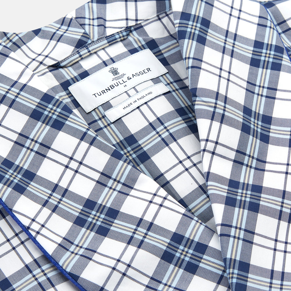 The Turnbull & Asser Blue Check Cotton Gown features long sleeves, a knee-length cut, shawl collar, and matching waist belt in a blue check pattern, shown against a plain white background.