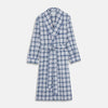 View 1 of product The Turnbull & Asser Blue Check Cotton Gown features long sleeves, a knee-length cut, shawl collar, and matching waist belt in a blue check pattern, shown against a plain white background.