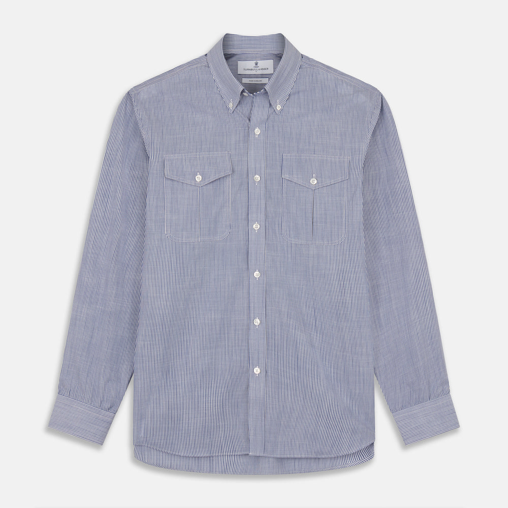 Turnbull & Asser’s Indigo Chambray Stripe Weekend Fit Shirt with Dorset collar features thin white pinstripes, two button-flap chest pockets, buttoned cuffs, and relaxed styling—presented flat on a white background.