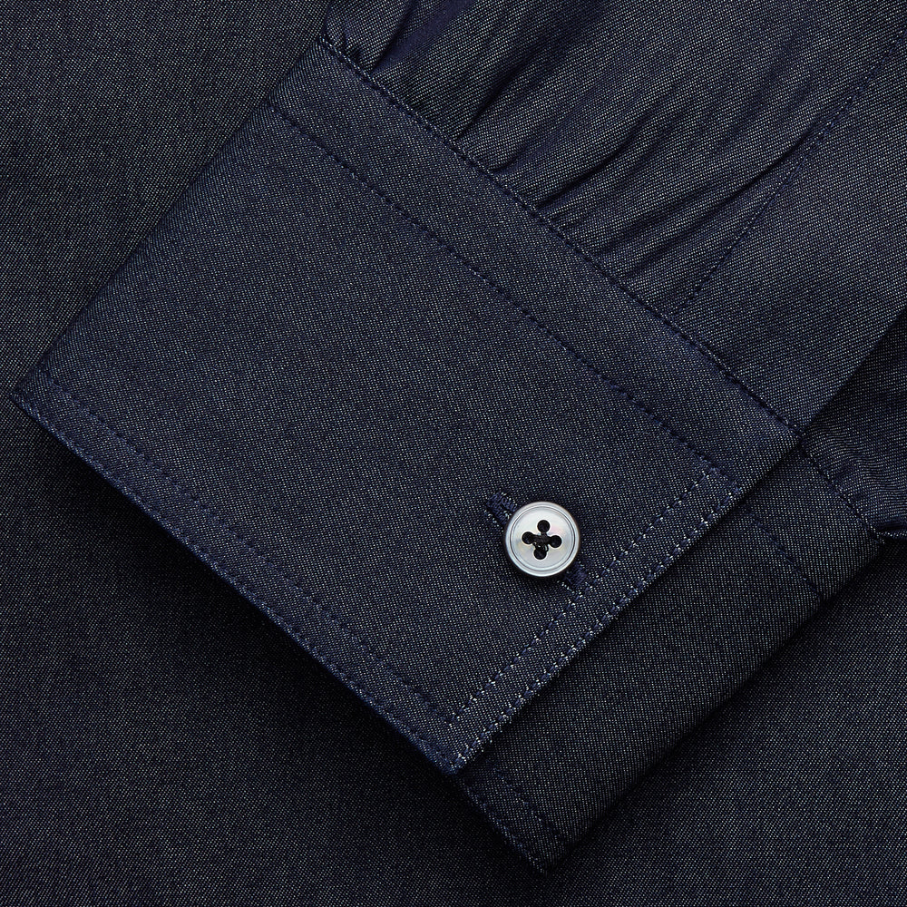 The Turnbull & Asser Navy Chambray Weekend Fit Shirt features a Dorset collar, long sleeves with 1-button cuffs, and two button-flap chest pockets. This officer’s shirt is displayed flat on a white background.