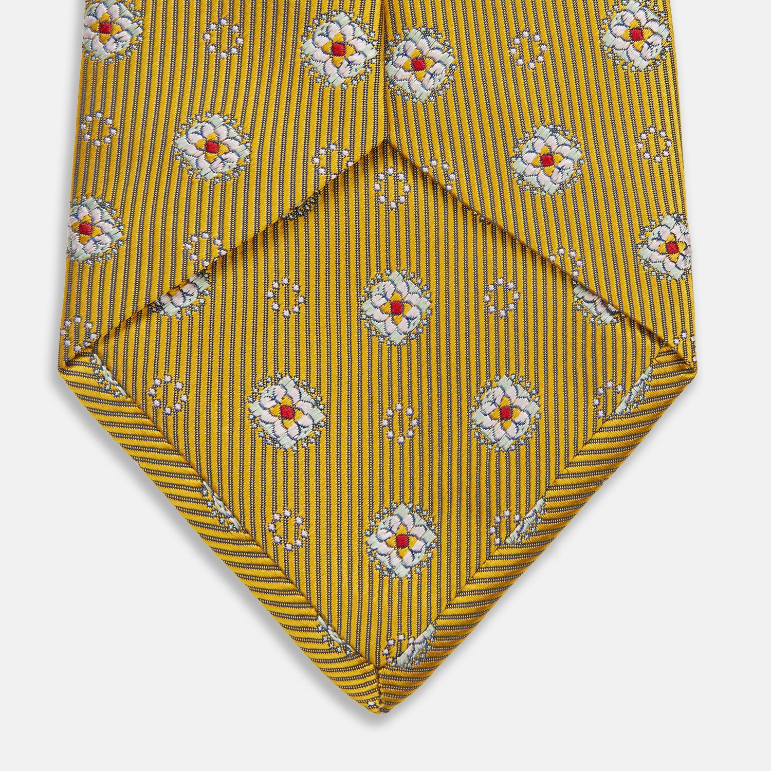 View 4 of product The Yellow Multi Floral Motif Silk Tie by Turnbull & Asser features subtle diagonal stripes and small white, blue, and orange floral motifs—a perfect summer palette, shown rolled up on a plain white background.
