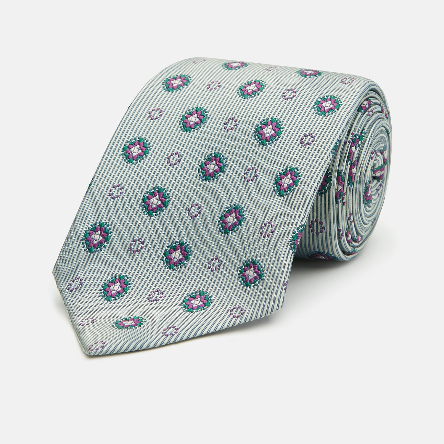 View 1 of product The Green Multi Floral Motif Silk Tie by Turnbull & Asser features light gray silk with thin diagonal stripes and a floral medallion pattern in pink, purple, and green—ideal for adding summer color to your outfit. Displayed rolled up on a white background.