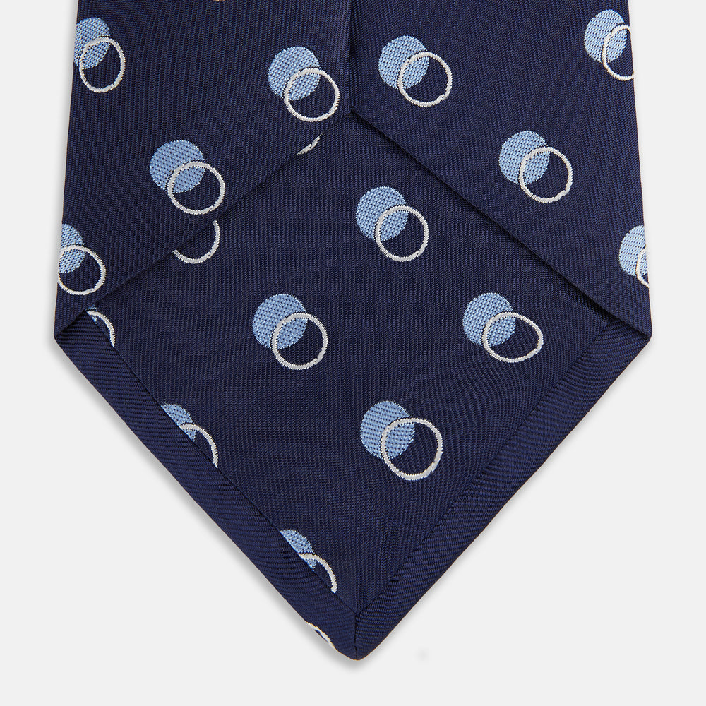The Turnbull & Asser Navy Multi Circle Silk Tie showcases overlapping light blue and white rings on navy silk—a stylish choice to elevate bold shirts or bring visual interest to your summer look.