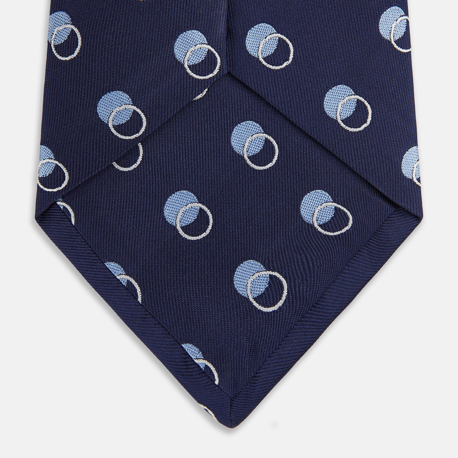 View 4 of product The Turnbull & Asser Navy Multi Circle Silk Tie showcases overlapping light blue and white rings on navy silk—a stylish choice to elevate bold shirts or bring visual interest to your summer look.