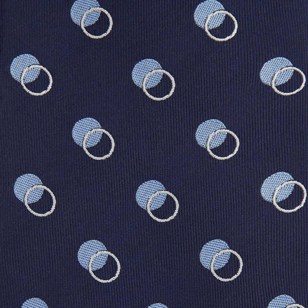 The Turnbull & Asser Navy Multi Circle Silk Tie showcases overlapping light blue and white rings on navy silk—a stylish choice to elevate bold shirts or bring visual interest to your summer look.