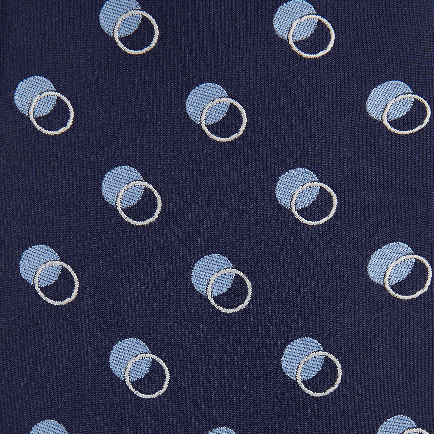 View 3 of product The Turnbull & Asser Navy Multi Circle Silk Tie showcases overlapping light blue and white rings on navy silk—a stylish choice to elevate bold shirts or bring visual interest to your summer look.